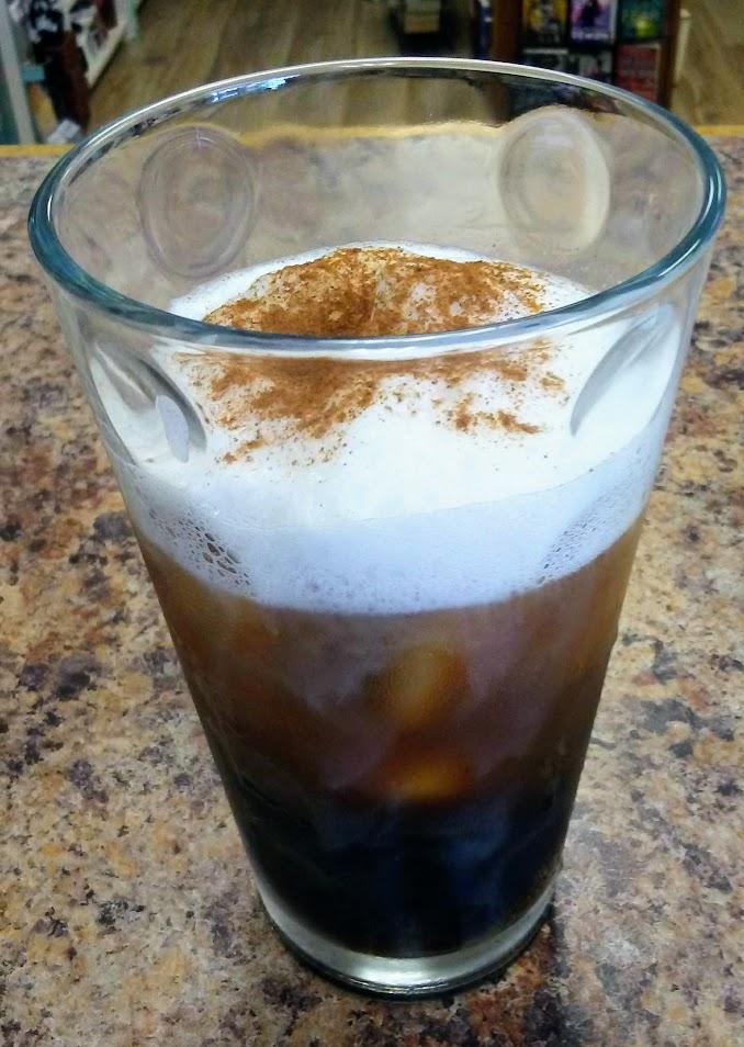 A glass of cold brew coffee topped with cinnamon-dusted foam